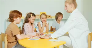 Profissional de apoio educativo especializado a trabalhar com crianças numa mesa de atividades
