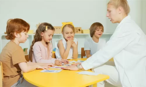 Profissional de apoio educativo especializado a trabalhar com crianças numa mesa de atividades