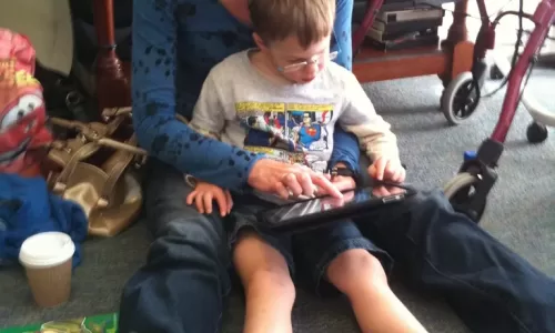 Mae com filho com deficiencia a usar tablet em casa - apoio parental PCD