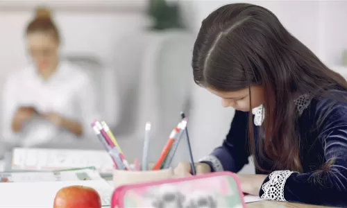 Menina a estudar em casa com a mãe por perto: homeschooling NEE Portugal